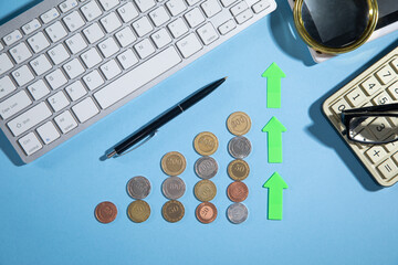 Wall Mural - Coins, growth arrow and business objects on the blue background. Business. Finance