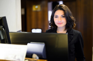 Happy female receptionist standing at hotel counter