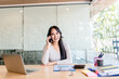 © EKKAPON - A business woman using a smartphone and smiling while working in the office