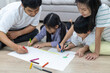 © Anupa - Father and mother are  teaching children to draw a picture at home and relax with they son to do home work by draw and paint, family , kid , education concept. children's creativity. happy family.