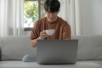 Work at home young asian man working on laptop computer while sitting at home Morning lifestyle