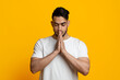 Portrait of religious middle eastern young man praying on yellow