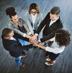 Wall Mural - Teamwork trumps it all. High angle shot of a group of businesspeople joining their hands together in a huddle.