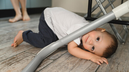 Happy mom and cheerful baby in the kitchen. Mother's love. The child is restless. Baby hides under the table from mom