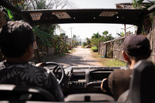 Hispanic Men In Car Driving Along Road In Countryside