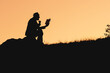 silhouette of a sitting man in nature on an orange background