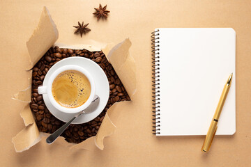 Wall Mural - Cup of coffee and beans in torn paper. Coffee with espresso in cardboard background