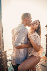 Beautiful couple in love hugs and kisses under the streams of water in a luxury spa hotel on their honeymoon, vacation in the tropics. Selective focus