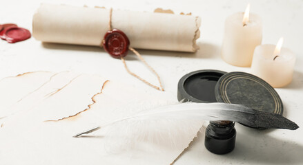 Paper sheet, quill, ink, scroll and candles on light table