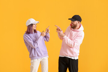 Wall Mural - Cool young couple in hoodies on color background