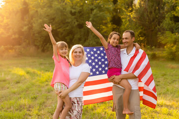 Wall Mural - Happy family with the American flag in a wheat field at sunset. Independence Day, 4th of July.