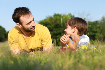 Sticker - Little boy with rugby ball and his father lying on green grass in park