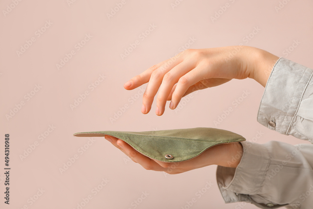 Woman with reusable menstrual pad on pink background