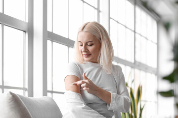 mature woman applying nicotine patch at home. smoking cessation