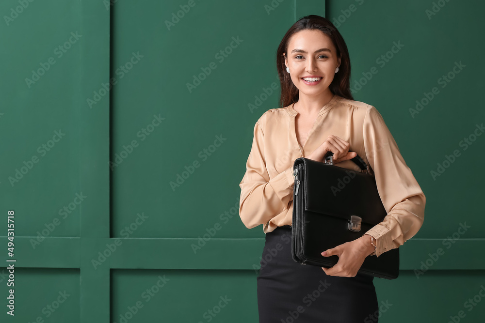 Pretty young businesswoman with briefcase on green background