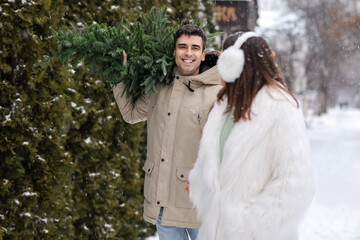 Sticker - Young woman and her boyfriend carrying Christmas tree on snowy winter day