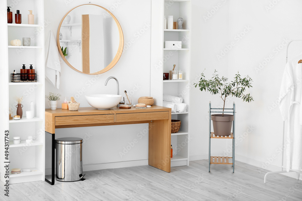 Stylish interior of bathroom with shelf units and table with different bath supplies