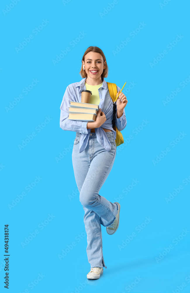 Female student with books on blue background