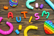 © Pixel-Shot - Word AUTISM with toys on dark wooden background