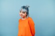 © bodnarphoto - Beautiful girl in orange clothes and with blue hair stands on a colored background and looks at the camera with a smile on his face.