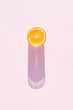 Leinwandbild Motiv Glass of drink with orange on a pink background. Aesthetic long shadow glass summer concept.