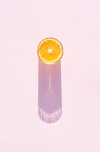 Glass Of Drink With Orange On A Pink Background. Aesthetic Long Shadow Glass Summer Concept.