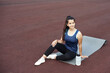 © etonastenka - Relaxation after outdoor yoga practice. Woman resting on yoga mat sitting in the stadium