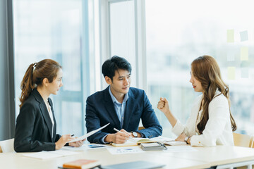 Wall Mural - group of four happy young asian corporate people teammates meeting discussing business in office.