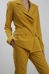 Female model wearing yellow tailored suit. Studio shot.	