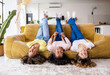 Happy multiracial best friends laying upside down on sofa and smiling at home during the weekend. Young diverse women group laying at the couch while having party at home