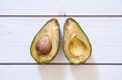 A rotten avocado on a light wooden background. The overripe avocado is cut in half. The core is in the fruit. 