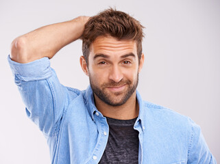 Poster - Hes a cool customer. Studio shot of a handsome young man scratching his head against a gray background.