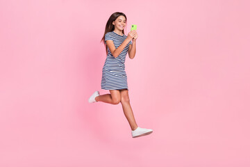 Canvas Print - Photo of shiny sweet girl wear striped dress jumping high typing modern device isolated pink color background