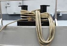 Black Mooring Bollards On A Gray Ship Wrapped With Ropes