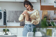 © nenetus - Beautiful woman eating noodles with chopsticks while standing in the kitchen at home.