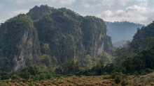 Scenic Landscape Panorama Of Beautiful Limestone Mountain With Blooming Mango Orchard In Foreground In Rural Agricultural Valley, Chiang Dao Countryside, Chiang Mai, Thailand