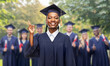 © Syda Productions - education, graduation and people concept - happy graduate student woman in mortarboard and bachelor gown pointing finger up over group of bachelors at park on background