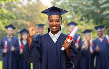 Wall Mural - education, graduation and people concept - happy graduate student woman in mortarboard and bachelor gown with diploma showing ok gesture over white background