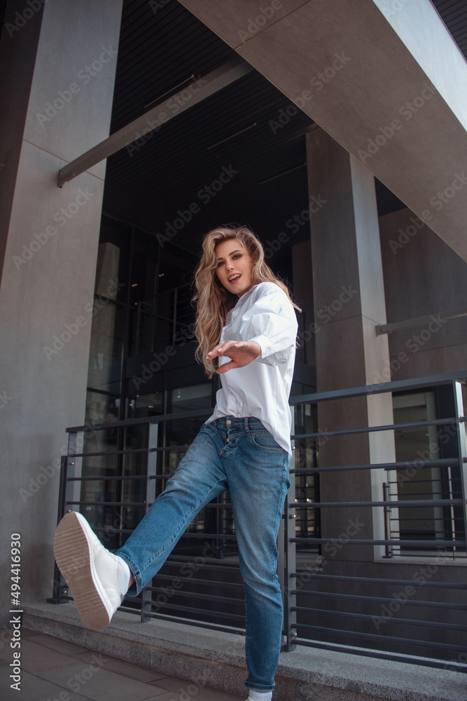 modern student. young blonde girl in white shirt and blue jeans is ...