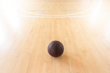 Basketball on hardwood court floor with natural lighting. Horizontal sport theme poster, greeting cards.