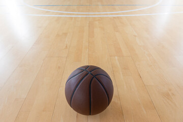 Basketball on hardwood court floor with natural lighting. Horizontal sport theme poster, greeting cards.