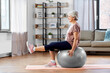 © Syda Productions - sport, fitness and healthy lifestyle concept - smiling senior woman training by sitting on exercise ball at home