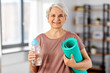 © Syda Productions - sport, fitness and healthy lifestyle concept - smiling senior woman with yoga mat and bottle of water at home