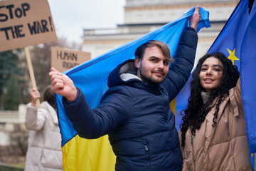 Wall Mural - Man and woman covered with EU and Ukraine flags and showing peace sign