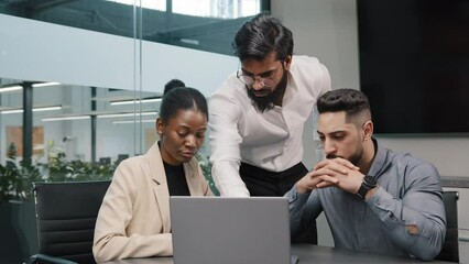 Arab man coach corporate trainer boss leader teacher mentor teaching interns managers employees use online application software shows in laptop discussing company education studying project in office