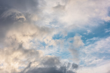 Wall Mural - scenic view to clouds illuminated by sunset in blue sky. nature background of cloudy sky in sunrise.