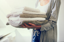 Because You Just Cant Go Without Clean Towels. Cropped Shot Of A Young Woman Holding A Pile Of Clean Towels.