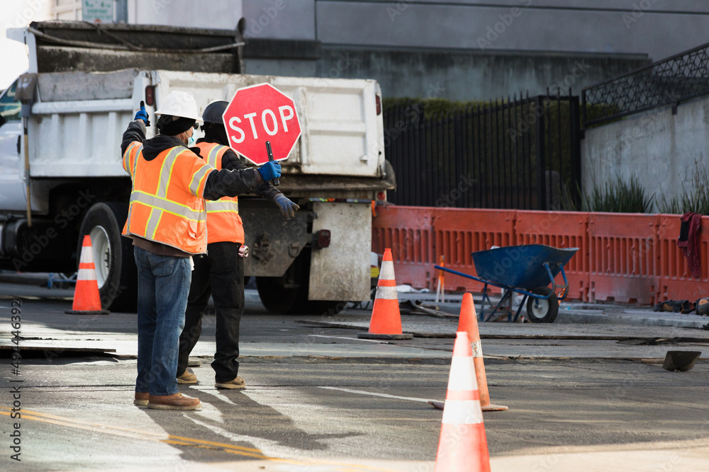 Avoid. Sign Workers Construction workers with reflective vests and helmets holding a stop ...