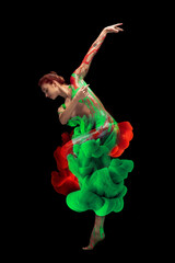 Wall Mural - Portrait of young tender woman covered with red and green paint and dye splah dancing isolated over black background