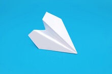 White Paper Plane On A Blue Background In The Center. Paper Origami In The Form Of A Small Airplane. Concept Of Travel Or Freedom Of Decision